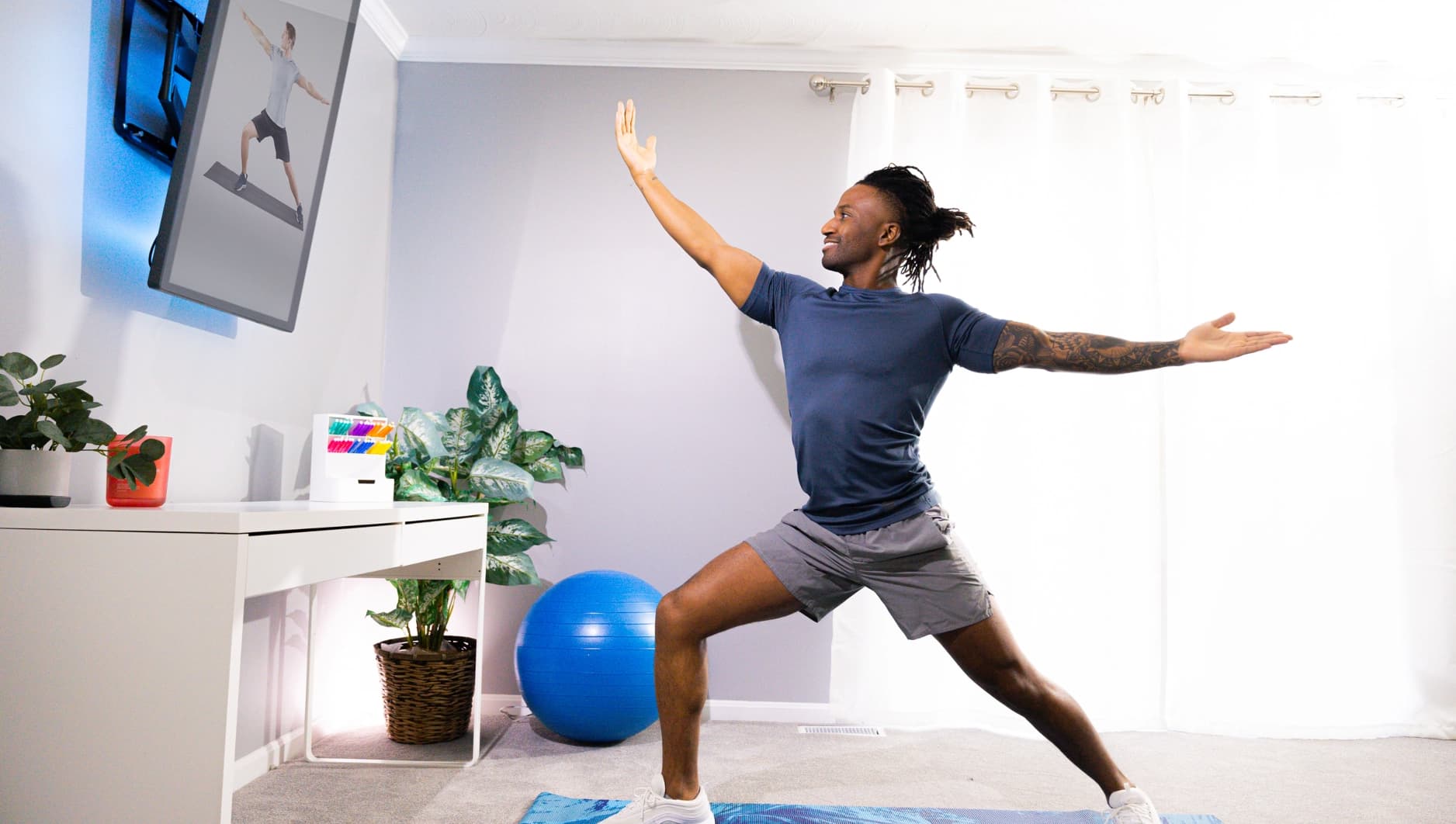 roflect-tv-mirror-03 Man doing yoga while following a video on a Roflect mirror TV screen in a home office.
